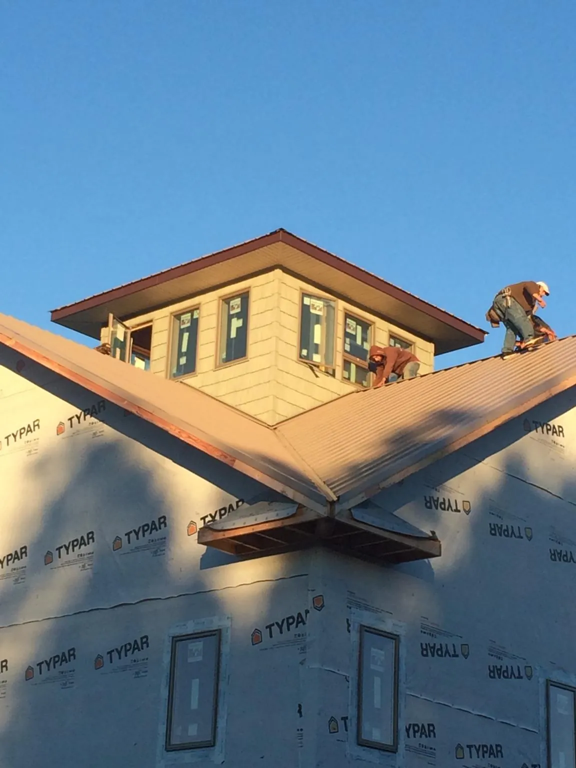 Roofers working around a rooftop cupola on a new metal roof at sunset — Roof Waterproofing in Morrison by Roofing Brothers